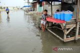 Sejumlah warga melintasi genangan air saat banjir rob di Medan Belawan, Sumatera Utara, Rabu (29/3/2024). Badan Meteorologi Klimatologi dan Geofisika (BMKG) Stasiun Meteorologi Klas II Maritim Belawan memperkirakan banjir rob yang melanda daerah tersebut akan berlangsung hingga 30 Maret 2024 dan meminta masyarakat agar waspada dengan tinggi air yang mencapai 2,6 meter. ANTARA FOTO/Yudi Manar