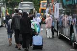 Sejumlah pemudik berjalan menuju bus saat Mudik Asyik Bersama BUMN 2024 di Surabaya, Jawa Timur, Jumat (5/4/2024). PT Perkebunan Nusantara (PTPN) I Regional 5 bersama PTPN I Regional 4 menyediakan sepuluh bus gratis untuk 401 pemudik yang pulang ke kampung halamannya dengan tujuan untuk mengalihkan pemudik menggunakan kendaraan roda dua ke moda angkutan massal yang lebih aman. Antara Jatim/Didik Suhartono/um