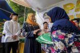 Ketua Muslimat Nahdlatul Ulama Khofifah Indar Parawansa (dua kiri) memberikan paket sembako kepada warga saat gelaran Pasar Murah Pemprov Jatim di Tuban, Jawa Timur, Jumat (5/4/2024). Pemerintah setempat menggelar pasar murah Ramadhan dengan menyediakan ratusan paket sembako dengan harga dibawah pasar guna menekan laju inflasi sekalgus menstabilkan harga jelang Lebaran 1445 H.  Antara Jatim/Muhammad Mada/um