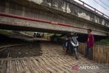 Pengendara motor menyeberang jalur pantura melalui kolong jembatan di desa Larangan, Indramayu, Jawa Barat, Jumat (6/4/2024). Penyeberangan alternatif yang dibuat secara swadaya tersebut digunakan pengendara yang hendak menyebrang atau putar arah di jalur pantura. ANTARA FOTO/Dedhez Anggara/agr