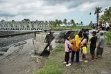 Warga mengamati kondisi Jembatan Mujur II di Lumajang, Jawa Timur, Jumat (19/4/2024). Jembatan penghubung Desa Kloposawit dan Desa Tumpeng tersebut putus akibat diterang banjir lahar hujan Gunung Semeru pada Kamis (18/4). Antara Jatim/Irfan Sumanjaya/um