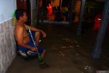 Warga duduk di teras rumahnya yang terendam banjir di Manguharjo, Kota Madiun, Jawa Timur, Selasa (23/4/2024). Sebanyak 38 rumah warga yang dihuni sekitar 150 jiwa di wilayah tersebut terendam banjir akibat hujan deras sehingga sungai meluap. Antara Jatim/Siswowidodo/mas.