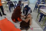 Pelajar bersama gurunya bersiap melakukan evakuasi  seorang siswa yang terluka saat berlangsung simulasi evakuasi mandiri di SMA 1 Lhoknga, kabupaten Aceh Besar, Aceh, Jumat (26/4/2024). Simulasi gempa dan tsunami yang rutin digelar setiap bulan pada tanggal 26 di sekolah tersebut  untuk  meningkatkan kewaspadaan dan pengurangan resiko bencana. ANTARA FOTO/Ampelsa.