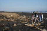 Sejumlah wisatawan melintas di dekat tumpukan sampah saat mengunjungi Pantai Bambang di Lumajang, Jawa Timur, Minggu (12/5/2024). Menurut warga setempat, sudah tiga pekan terakhir sampah yang terbawa banjir lahar hujan Gunung Semeru tersebut menumpuk di pesisir pantai itu.  Antara Jatim/Irfan Sumanjaya/um