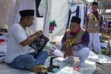 Pekerja memperbaiki tas milik jamaah calon haji di Asrama Haji Embarkasi Kertajati, Indramayu, Jawa Barat, Rabu (15/5/2024). Jasa perbaikan tas atau menambahkan tali pada tas milik jamaah calon haji tersebut dikenakan biaya Rp25 ribu per tas. ANTARA FOTO/Dedhez Anggara/agr