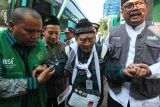 Petugas membantu calon haji bernama Hardjo Mislan (109) (tengah) berjalan menuju gedung Mina, Asrama Haji Embarkasi Surabaya (AHES), Surabaya, Jawa Timur, Rabu (15/5/2024). Calon haji yang berumur 109 tahun itu merupakan calon haji tertua di Indonesia dari kloter 19 asal Kabupaten Ponorogo dan dijadwalkan berangkat ke Tanah Suci pada Kamis (16/5). Antara Jatim/Didik Suhartono/mas.