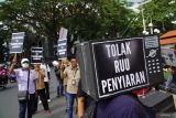 Sejumlah wartawan melakukan teatrikal menggunakan miniatur televisi saat aksi unjuk rasa tolak Rancangan Undang-undang (RUU) Penyiaran di Depan Gedung Balai Kota Malang, Malang, Jawa Timur, Jumat (17/5/2024). Wartawan yang tergabung dalam organisasi Pewarta Foto Indonesia (PFI), Ikatan Jurnalis Televisi Indonesia (IJTI), Aliansi Jurnalis Independen (AJI), dan Persatuan Wartawan Indonesia (PWI) di daerah tersebut menggelar aksi untuk menolak pasal-pasal dalam RUU penyiaran yang dinilai berpotensi mengalangi tugas jurnalistik dan kebebasan pers. Antara Jatim/Irfan Sumanjaya/mas.