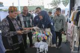 Asisten Perekonomian dan Pembangunan Sekda Aceh Zulkifli (kiri) didampingi CEO Rumah BUMN Aceh Helmi Fadli (kedua kanan) saat melihat produk ecoprint produksi dari UMKM Rumah BUMN Sabang pada acara Karya Nyata Festival Vol.7 di Lapangan Blang Padang, Banda Aceh, Aceh, Sabtu (1/6/2024). Karya Nyata Festival Vol.7 yang digagas oleh Kementerian BUMN melibatkan 86 pelaku UMKM dari seluruh Aceh sebagai wujud keseriusan pemerintah melalui Rumah BUMN dalam mendukung sektor UMKM di Indonesia untuk naik kelas sehingga bisa tumbuh lebih maju. ANTARA FOTO/Khalis Surry