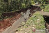 Suasana jalan terputus akibat longsor di Pasirjati, Cijengkol, Caringin, Kabupaten Sukabumi, Jawa Barat, Rabu (26/6/2024). Intensitas hujan yang tinggi mengakibatkan jalan penghubung antarkecamatan Caringin dan Cibadak longsor sedalam 10 meter sehingga menyebabkan akses jalan terputus. ANTARA FOTO/Henry Purba/agr
