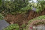 Warga berdiri di dekat jalan longsor di Desa Puspamukti, Kabupaten Tasikmalaya, Jawa Barat, Minggu (30/6/2024). Intensitas hujan yang tinggi mengakibatkan jalan penghubung antarkampung longsor sehingga menyebabkan akses jalan di Kampung Parung, Kiarabongkok, Salawi, Kecamatan Cilaglontang, terisolir karena tidak bisa dilalui. ANTARA FOTO/Adeng Bustomi/agr