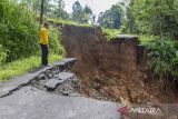 Warga berdiri di dekat jalan longsor di Desa Puspamukti, Kabupaten Tasikmalaya, Jawa Barat, Minggu (30/6/2024). Intensitas hujan yang tinggi mengakibatkan jalan penghubung antarkampung longsor sehingga menyebabkan akses jalan di Kampung Parung, Kiarabongkok, Salawi, Kecamatan Cilaglontang, terisolir karena tidak bisa dilalui. ANTARA FOTO/Adeng Bustomi/agr