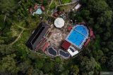 Foto udara sejumlah pengunjung berendam di pemandian air panas Cangar, Batu, Jawa Timur, Minggu (30/6/2024). Destinasi wisata yang terletak di kawasan Taman Hutan Raya Raden Soerjo itu kini telah selesai direnovasi oleh Pemerintah setempat sehingga target kunjungan wisatawan 2024 sebanyak 12 juta orang di kawasan wisata unggulan Jawa Timur tersebut diharapkan dapat tercapai. Antara Jatim/Muhammad Mada/um 