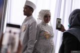 Sepasang pengantin berpose saat nikah massal di Surabaya, Jawa Timur, Selasa (2/7/2024). Pemkot Surabaya menggelar sidang isbat nikah massal sekaligus resepsi bagi 330 pasangan pengantin dari berbagai golongan umur. Antara Jatim/Didik Suhartono/um