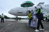 Petugas membantu jamaah haji yang tergabung dalam kelompok terbang (kloter) 01-BTJ turun dari pesawat Garuda Indonesia setibanya di Bandara Internasional Sultan Iskandar Muda (SIM) Aceh Besar, Aceh, Rabu (10/7/2024). Sebanyak 393 jamaah haji kloter pertama asal Kabupaten Aceh Besar dan Kota Sabang, debarkasi Aceh kembali ke Tanah Air usai menunaikan ibadah haji. ANTARA FOTO/Khalis Surry
