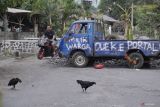 Warga melintasi jalan yang diblokade menggunakan pikap di Desa Condro, Kecamatan Pasirian, Lumajang, Jawa Timur, Kamis (11/7/2024). Aksi blokade jalan menggunakan pohon pisang, mobil pikap, dan ban bekas sejauh 1,2 kilometer tersebut sebagai bentuk protes warga akibat jalan rusak yang tak kunjung diperbaiki selama setahun terakhir.  ANTARA Jatim/Irfan Sumanjaya/mas.