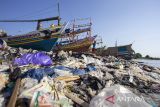 Nelayan memperbaiki perahu yang disandarkan sekitar pantai yang dipenuhi sampah plastik di Pantai Dadap, Juntinyuat, Indramayu, Jawa Barat, Jumat (12/7/2024). Nelayan setempat mengeluhkan banyaknya sampah plastik yang menumpuk di bibir pantai sehingga menghambat aktivitas nelayan saat bersandar dan menurunkan ikan. AANTARA FOTO/Dedhez Anggara/agr