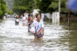 Sejumlah warga melewati jalan yang tergenang banjir di Kota Gorontalo, Gorontalo, Kamis (11/7/2024). BPBD Kota Gorontalo mendata sebanyak 1.669 KK atau mencapai 12.487 jiwa terdampak banjir yang menggenangi Kecamatan Kota Selatan, Hulonthalangi, Dumbo Raya, Kota Barat, Kota Timur, dan Dungingi akibat luapan sungai Bulango dan Bone. ANTARA FOTO/Adiwinata Solihin/tom.