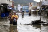 Sejumlah warga melewati jalan yang tergenang banjir di Kota Gorontalo, Gorontalo, Kamis (11/7/2024). BPBD Kota Gorontalo mendata sebanyak 1.669 KK atau mencapai 12.487 jiwa terdampak banjir yang menggenangi Kecamatan Kota Selatan, Hulonthalangi, Dumbo Raya, Kota Barat, Kota Timur, dan Dungingi akibat luapan sungai Bulango dan Bone. ANTARA FOTO/Adiwinata Solihin/tom.