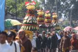 Warga mengarak gunungan berisi hasil bumi saat kirab dan ritual budaya di kawasan Situs Calonarang, Kediri, Jawa Timur, Selasa (16/7/2024). Kegiatan di kawasan cagar budaya situs Calonarang tersebut dilakukan setiap tanggal 10 bulan Suro penanggalan Jawa. Antara Jatim/Prasetia Fauzani/um