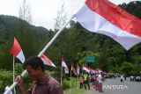 Sejumlah warga mengibarkan bendera di sisi kiri dan kanan  jalan nasional pada kegiatan Pencanangan Gerakan Nasional Pembagian 10 juta Bendera Merah Putih di kawasan gunung Geurutee, kabupaten Aceh Besar, Aceh, Rabu (17/7/2024). Gerakan Nasional pembagian bendera yang digagas Kementerian Dalam Negeri untuk memeriahkan HUT ke-79 Kemerdekaan RI di daerah melibatkan seluruh  kepala desa dan  tokoh pemuda, TNI dan Polri serta ormas itu guna membangkitkan semangat kebersamaan, nasionalisme dan cinta tanah air. ANTARA FOTO/Ampelsa.