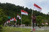 Sejumlah warga mengibarkan bendera di sisi kiri dan kanan  jalan nasional pada kegiatan Pencanangan Gerakan Nasional Pembagian 10 juta Bendera Merah Putih di kawasan gunung Geurutee, kabupaten Aceh Besar, Aceh, Rabu (17/7/2024). Gerakan Nasional pembagian bendera yang digagas Kementerian Dalam Negeri untuk memeriahkan HUT ke-79 Kemerdekaan RI di daerah melibatkan seluruh  kepala desa dan  tokoh pemuda, TNI dan Polri serta ormas itu guna membangkitkan semangat kebersamaan, nasionalisme dan cinta tanah air. ANTARA FOTO/Ampelsa.