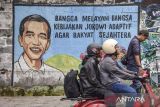 Pengendara melintas di dekat mural bertema kinerja pemerintahan Presiden Jokowi di Kabupaten Ciamis, Jawa Barat, Kamis (18/7/2024). Mural tersebut banyak ditemukan di sejumlah titik di pusat kota sebagai wujud ekspresi ucapan dari warga atas apresiasi kinerja pemerintah di era Presiden Joko Widodo. ANTARA FOTO/Adeng Bustomi/agr
