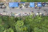 Foto udara suasana median jalan masuk ke Pasar Rakyat Talang Banjar yang dipadati pedagang kaki lima di Jambi, Rabu (17/7/2024). Pasar Rakyat Talang Banjar yang selesai dibangun pada 2017 dengan daya tampung sekitar 1.000 pedagang tersebut hingga kini belum berfungsi optimal dengan keterisian lapak kurang dari 30 persen karena sejumlah pedagang lebih memilih mendirikan bangunan liar di tepi jalan raya. ANTARA FOTO/Wahdi Septiawan/rwa.