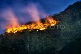 Api membakar hutan dan lahan (karhutla) lereng gunung Sipiso-piso di Merek, Karo, Sumatera Utara, Kamis (18/7/2024) malam. Menurut data Badan Penanggulangan Bencana Daerah (BPBD) Karo, api yang membakar sekitar 20 hektare hutan dan lahan di lereng gunung tersebut berasal dari Dusun Simpang Bage dan Nagori Sinar Naga Mariah, Kabupaten Simalungun yang selanjutnya merambat dengan cepat ke wilayah Gunung Sipiso-piso, sementara hingga Jumat (19/7) dini hari petugas masih mengupayakan pemadaman. ANTARA FOTO/Fransisco Carolio/aww.
