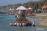 Sejumlah umat Hindu mengarak tempat pembakaran jenazah saat melintasi pantai pada upacara ngaben massal di Desa Adat Karangsari, Nusa Penida, Kabupaten Klungkung, Bali, Kamis (18/7/2024). Upacara ngaben massal tersebut digelar setiap lima tahun sekali dengan berjalan melintasi pantai. ANTARA FOTO/Nyoman Hendra Wibowo/wsj.