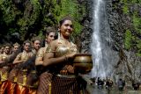 Sejumlah remaja membawa kendi berisi air yang diambil dari air terjun saat prosesi ritual Siraman Sedudo di Nganjuk, Jawa Timur, Sabtu (20/7/2024). Ritual yang dilaksanakan setahun sekali saat bulan Suro (penanggalan Jawa) sejak zaman kerajaan Majapahit itu sebagai tolak bala dan simbol pembersihan diri. ANTARA Jatim/Muhammad Mada/mas.