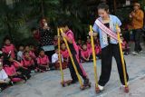 Putri Anak Indonesia Budaya 2022 Karina Aliya Afandi (kedua dari kanan) bersama pelajar bermain permainan tradisional Egrang di SD Negeri Airlangga I, Surabaya, Jawa Timur, Senin (22/7/2024). Pengenalan permainan tradisional kepada pelajar di antaranya permainan Egrang, Balogo bersama Komunitas Kampoeng Dolanan dan juga belajar mewarna kain menggunakan teknik Jumputan itu untuk menyambut Hari Anak Nasional. Antara Jatim/Didik Suhartono/um