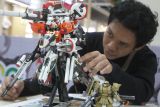 Peserta menata pose mainan action figure robot Gundam di salah satu stan dalam festival mainan bertajuk Artofest 2024 di Hall Malang Town Square, Jawa Timur, Senin (22/7/2024). Festival mainan yang berlangsung selama tujuh hari tersebut menampilkan berbagai kegiatan seperti pameran, lomba serta pelatihan merakit mainan dari berbagai komunitas penggemar mainan, lembaga pendidikan maupun perkumpulan seniman. ANTARA Jatim/Ari Bowo Sucipto/mas.