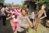 Kapolsek Plemahan AKP Bowo Wicaksono (kanan) memainkan wayang edukasi kepada pelajar Taman Kanak-kanak di Omah Among Roso, Desa Puhjarak, Kediri, Jawa Timur, Selasa (23/7/2024). Pentas wayang edukasi menceritakan sifat kebaikan melawan keburukan yang diawali dengan mewarnai bersama tersebut sebagai upaya mendekatkan polisi kepada anak-anak sekaligus memperingati Hari Anak Nasional. Antara Jatim/Prasetia Fauzani/um