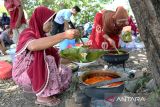 Petani menuangkan gulai kari ke dalam nasi yang dibungkus menggunakan daun pisang untuk dihidangkan  pada tradisi Kenduri Blang (sawah)  di desa Lam Aling, kabupaten Aceh Besar, Aceh, Kamis (25/7/2024).  Tradisi Kenduri Blang atau kenduri sawah saat padi mulai berperut atau bunting  dihadiri sejumlah kelompok tani dengan ritual menggelar zikir dan doa bersama itu bertujuan untuk mendapatkan berkah agar hasil panen melimpah. ANTARA FOTO/Ampelsa.