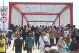 Warga berjalan kaki melewati jembatan Jongbiru yang dibangun di atas sungai Brantas saat peresmian jembatan Jongbiru di Kediri, Jawa Timur, Jumat (26/7/2024). Jembatan Jongbiru yang dibangun dengan anggaran sebesar Rp27 miliar dari Anggaran Pendapatan Belanja Negara (APBN) tahun 2023-2024 tersebut telah diresmikan sebagai upaya mendukung lalu lintas kendaraan menuju bandara Dhoho sekaligus penghubung antara kota dengan kabupaten Kediri. ANTARA Jatim/Prasetia Fauzani/mas.