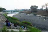 Sejumlah warga berada di kawasaan Sungai Madiun di Kota Madiun, Jawa Timur, Jumat (26/7/2024). Sungai yang merupakan anak sungai Bengawan Solo tersebut sejak sebulan terakhir airnya terus menyusut hingga sebagian dasarnya mengering akibat musim kemarau, dan setiap hari dikunjungi warga untuk bersantai. Antara Jatim/Siswowidodo/um