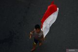 Seoang anak mengibarkan Bendera Merah Putih yang diperolehnya saat Parade Senja dan pembagian Bendera Merah Putih di Kota Madiun, Jawa Timur, Sabtu (27/7/2024). Pemkot Madiun membagikan 10.000 Bendera Merah Putih sebagai gerakan nasional untuk memeriahkan HUT ke-79 Kemerdekaan RI guna membangkitkan semangat nasionalisme serta kecintaan pada Negara Kesatuan Republik Indonesia (NKRI). Antara Jatim/Siswowidodo/um