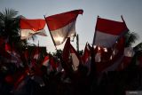 Warga mengibarkan Bendera Merah Putih yang diperolehnya saat Parade Senja dan pembagian Bendera Merah Putih di Kota Madiun, Jawa Timur, Sabtu (27/7/2024). Pemkot Madiun membagikan 10.000 Bendera Merah Putih sebagai gerakan nasional untuk memeriahkan HUT ke-79 Kemerdekaan RI guna membangkitkan semangat nasionalisme serta kecintaan pada Negara Kesatuan Republik Indonesia (NKRI). Antara Jatim/Siswowidodo/um