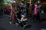 Seorang perempuan mendorong stroller anaknya di kawasan Pahlawan Street Center saat digelar Car Free Night Kota Madiun, Jawa Timur, Sabtu (27/7/2024). Pemkot Madiun menggelar kegiatan tersebut untuk meningkatkan kunjungan wisata guna meningkatkan perekonomian masyarakat, terutama pelaku Usaha Mikro Kecil dan Menengah (UMKM) dan pekerja seni. Antara Jatim/Siswowidodo/um 