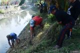 Sejumlah petugas gabungan dan relawan membersihkan Sungai Blender yang berada di perbatasan wilayah Kota dan Kabupaten Madiun,  Jawa Timur, Sabtu (10/8/2024). Petugas gabungan dari Badan Penanggulangan Bencana Daerah (BPBD), Balai Besar Wilayah Sungai (BBWS) Bengawan Solo, Dinas Pekerjaan Umum dan Penataan Ruang Kota, Dinas Lingkungan Hidup, TNI, Polri dan relawan membersihkan sampah, rumput dan tanaman di kawasan sungai sebagai upaya mengendalikan banjir saat musim hujan. Antara Jatim/Siswowidodo/mas.