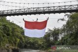 Warga membentangkan bendera Merah Putih di jembatan gantung Sukamenak, Kampung Benteng, Kecamatan Purbaratu, Kota Tasikmalaya, Jawa Barat, Minggu (11/8/2024). Pembentangan bendera Merah Putih berukuran 60 meter persegi tersebut dalam rangka persiapan upacara menyambut HUT Ke-79 RI. ANTARA FOTO/Adeng Bustomi/agr