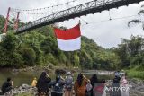 Warga memberikan hormat ke bendera Merah Putih raksasa di jembatan gantung Sukamenak, Kampung Benteng, Kecamatan Purbaratu, Kota Tasikmalaya, Jawa Barat, Minggu (11/8/2024). Pembentangan bendera Merah Putih berukuran 60 meter persegi tersebut dalam rangka persiapan upacara menyambut HUT Ke-79 RI. ANTARA FOTO/Adeng Bustomi/agr