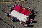 Sejumlah anak membentangkan bendera Merah Putih saat mengikuti kegiatan Sapa Desa komunitas Sobat Sosial di Ngluyu, Nganjuk, Jawa Timur, Minggu (11/8/2024). Aksi membentangkan bendera Merah Putih di salah satu daerah pelosok di Nganjuk tersebut merupakan bentuk upaya pemuda setempat untuk menanamkan semangat kemerdekaan dan cinta tanah air kepada masyarakat khususnya anak-anak di desa itu. ANTARA Jatim/Muhammad Mada/mas.