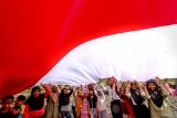 Sejumlah anak membentangkan bendera Merah Putih saat mengikuti kegiatan Sapa Desa komunitas Sobat Sosial di Ngluyu, Nganjuk, Jawa Timur, Minggu (11/8/2024). Aksi membentangkan bendera Merah Putih di salah satu daerah pelosok di Nganjuk tersebut merupakan bentuk upaya pemuda setempat untuk menanamkan semangat kemerdekaan dan cinta tanah air kepada masyarakat khususnya anak-anak di desa itu. ANTARA Jatim/Muhammad Mada/mas.