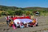 Sejumlah anak membentangkan bendera Merah Putih saat mengikuti kegiatan Sapa Desa komunitas Sobat Sosial di Ngluyu, Nganjuk, Jawa Timur, Minggu (11/8/2024). Aksi membentangkan bendera Merah Putih di salah satu daerah pelosok di Nganjuk tersebut merupakan bentuk upaya pemuda setempat untuk menanamkan semangat kemerdekaan dan cinta tanah air kepada masyarakat khususnya anak-anak di desa itu. ANTARA Jatim/Muhammad Mada/mas.