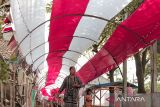 Warga melintas di lorong bendera Merah Putih di Kampung Selajambe, Desa Selajambe, Sukuluyu, Kabupaten Cianjur, Jawa Barat, Senin (12/8/2024). Lorong bendera Merah Putih sepanjang 200 meter hasil swadaya masyarakat tersebut dipasang dalam rangka menyemarakkan HUT ke-79 RI. ANTARA FOTO/Henry Purba/agr