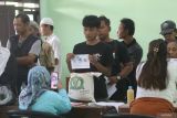 Petugas mendokumentasikan warga penerima manfaat saat pengambilan bantuan pangan cadangan beras di Balai Kelurahan Bangsal, Kota Kediri, Jawa Timur, Rabu (14/8/2024). Pemerintah daerah setempat bersinergi dengan Perum Bulog menyalurkan bantuan 336.320 kilogram beras periode bulan Agustus 2024 untuk 33.632 keluarga penerima manfaat. ANTARA Jatim/Prasetia Fauzani/mas.