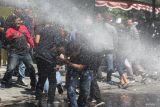 Sejumlah pengunjuk rasa menghindar semprotan air dari kendaraan taktis water canon saat simulasi sistem pengamanan kota (Sispamkota) di depan Kantor Komisi Pemilihan Umum (KPU) Kota Surabaya, Surabaya, Jawa Timur, Rabu (14/8/2024). Simulasi yang melibatkan TNI dan Polri itu untuk menunjukkan kesiapan mereka dalam mengamankan proses Pemilihan Kepala Daerah (Pilkada) 2024. ANTARA Jatim/Didik Suhartono/mas.