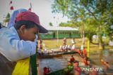 Sejumlah siswa SDN Basirih 10 menyaksikan peserta lomba balap perahu yang diisi tiga orang dengan jarak sekitar 15 meter, kemudian peserta berputar menuju garis finis di Sungai Jelai (Anak Sungai Martapura) Kelurahan Basirih Selatan, Kota Banjarmasin, Kalimantan Selatan, Sabtu (17/8/2024). Lomba balap perahu kecil yang diikuti 44 siswa SDN Basirih 10 tersebut dalam rangka memeriahkan HUT ke-79 Republik Indonesia. ANTARA/Abdul Hakim.