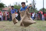 Sejumlah anak beradu cepat saat lomba balap karung di Desa Lamgapang, Krueng Barona Jaya, Aceh Besar, Aceh Minggu (18/8/2024). Perlombaan rakyat seperti balap karung, parut kelapa, estafet tepung terigu tersebut diikuti warga lintas usia, yang digelar untuk memeriahkan HUT ke 79 Kemerdekaan Republik Indonesia, sekaligus upaya dalam meningkatkan kekompakan antar sesama masyarakat. ANTARA FOTO/Khalis Surry